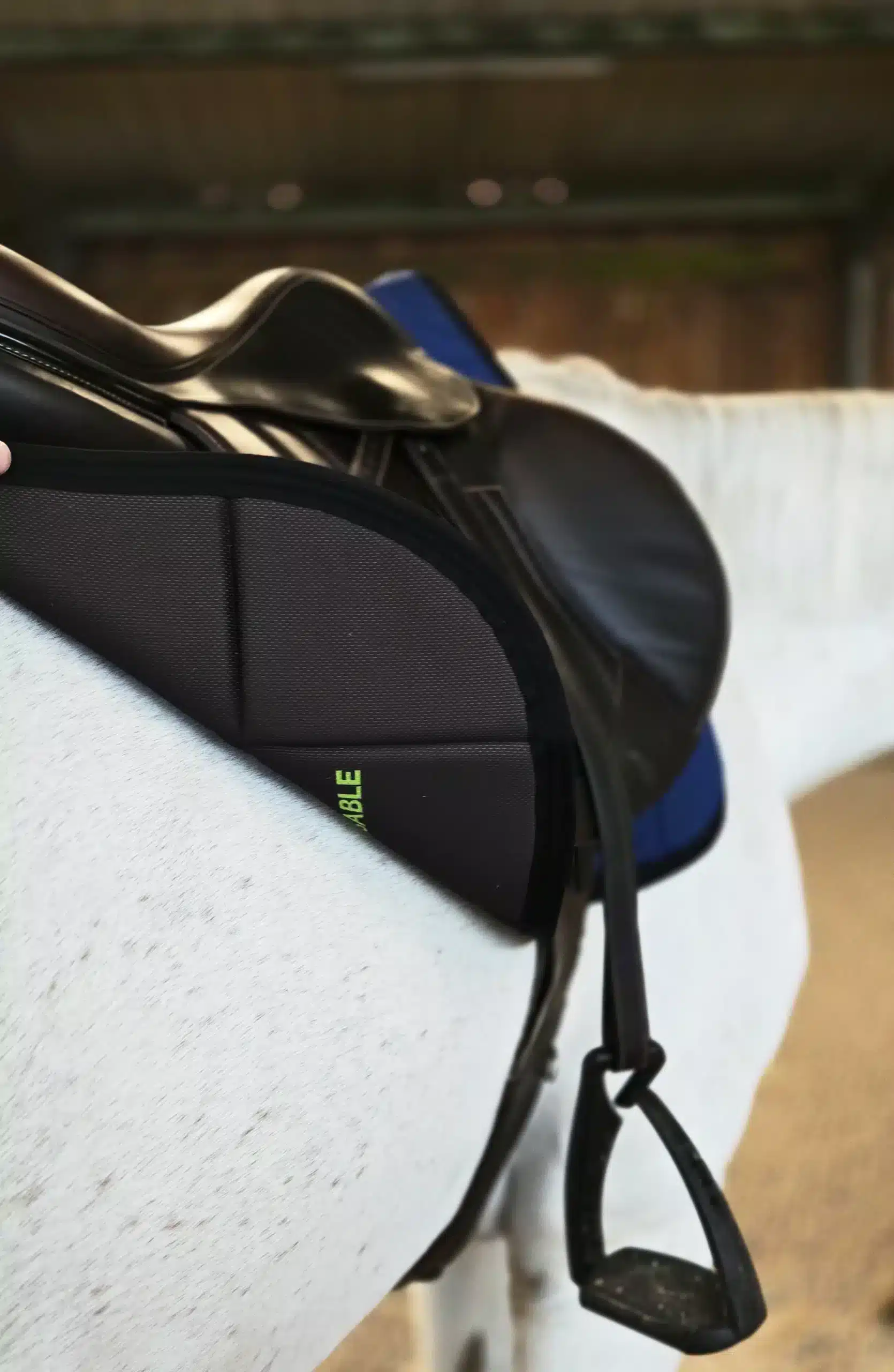 Zoom sur un tapis de selle EliteRide noir et ergonomique, équipé sous une selle d'équitation.